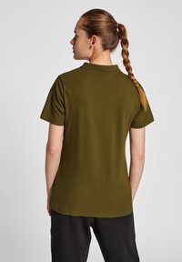 Olivgrön pikétröja med korta ärmar, krage och rak fåll. Slät tyg med en subtil stretch och inga synliga mönster.
