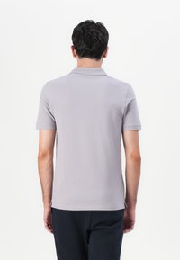 Grå polo-skjorte med korte ermer, spiss krage og rett nederkant. Stoffet ser glatt og lett ut.