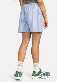 Blue and white striped shorts with an elastic waistband, featuring a loose fit and side pockets. Worn with green sneakers and white socks.
