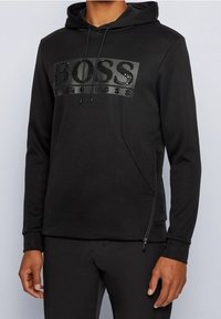 Czarna bluza z kapturem z textured logo z napisem "BOSS." Posiada przednią kieszeń i zamek na dole. Wykonana z miękkiego materiału.