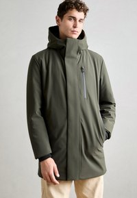 Olijfgroen waterdichte jas met een hoge kraag, zijzakken en een met rits sluitende borstzak. Glad materiaal en minimalistisch ontwerp.