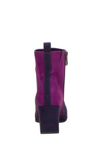Bottines en suède violet avec un talon carré, présentant une fermeture éclair latérale et un détail de bande contrastante en violet foncé. Texture lisse.