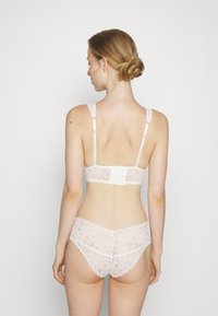 Bralette en dentelle et culottes assorties en crème doux. Comprend un design en dentelle délicate, des bretelles réglables et une fermeture à crochet à l'arrière.