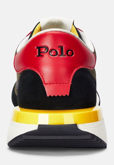 Zapatillas de hombre con ante negro y suela de goma amarilla. Presentan un talón de cuero rojo con el logo "Polo" y una forma general redondeada.