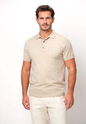 Polo de manga corta beige hecho de una tela suave, con un cuello y una tapeta de tres botones, diseño ajustado y dobladillo acanalado.
