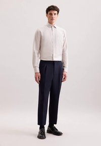 Jasnoszara koszula z kołnierzykiem i pionowymi paskami, zestawiona z ciemnogranatowymi spodniami. Model nosi czarne buty, stoi na neutralnym tle.