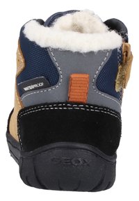 Waterdichte laarzen met een tan schoenen van suede, een grijze textielpaneel, blauwe accenten, een zwarte textuurzool en een witte bontvoering bij de kraag.