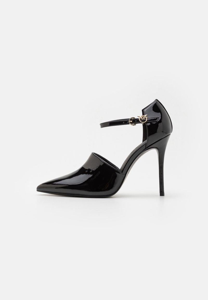 Scarpa col tacco alto in pelle verniciata nera con punta affilata, cinturino alla caviglia con accessori in oro e un design elegante e liscio.