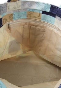 Textiel draagtas interieur met beige voering, ritszak en zijcompartimenten. Heeft een patchwork buitenkant in lichtblauw en tan.