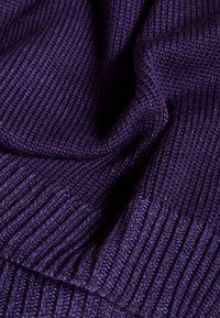 Tissu tricoté violet avec une texture côtelée, présentant une apparence douce et une finition lisse. Le matériau semble chaud et flexible.