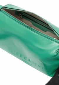 Grüne Leder-Crossbody-Tasche mit einem Reißverschluss oben, ausgestattet mit einer strukturierten Oberfläche und geprägtem Branding, ergänzt durch einen schwarzen Träger.