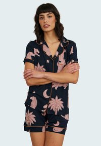Navyblaues Pyjama-Set mit hellrosa Mustern von Tieren und Pflanzen, mit kontrastierendem orangem Paspelband am Kragen und an den Shorts.