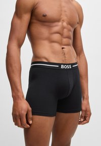 Black boxer briefs made of soft cotton with a fitted design. The waistband features the "BOSS" logo in white and gray stripes.