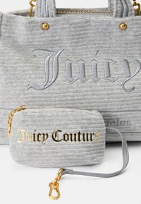 Szürke, textúrázott anyagból készült bevásárlótáska, kiemelkedő "Juicy" logóval és arany díszítésekkel; tartalmaz egy összeillő pici táskát, rajta arany betűkkel a "Juicy Couture" felirattal.