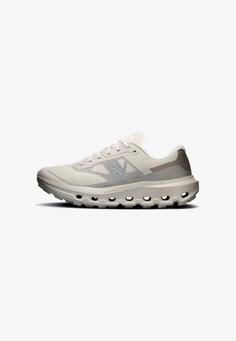 Chaussure de running beige clair avec tige en mesh respirant, fermeture à lacets et semelle coussinée munie de trous en forme de nuage pour l'absorption des chocs.