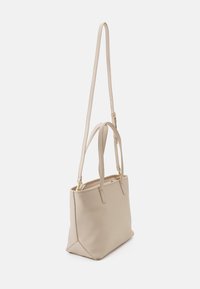 Beige faux läder tote-väska med två handtag och en lång justerbar rem. Har guldtonad hårdvara och en strukturerad rektangulär form.