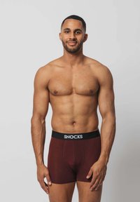Männer Boxershorts in Bordeauxrot mit einem schwarzen, elastischen Bund, auf dem der Text "SNOCKS" steht. Der Stoff wirkt glatt und hat ein figurbetontes Design.