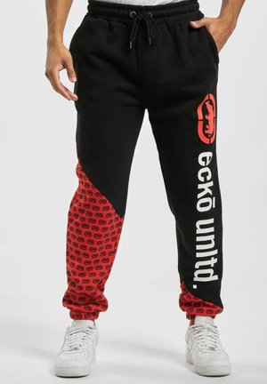 Pantaloni jogger neri con una sezione rossa decorata da motivi e loghi, vita elastica e testo bianco "eckō untd." su una gamba.