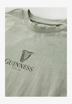 Vaaleanvihreä puuvillapaita, joka esittelee tummanvihreää Guinness-logoa ja "ESTD 1759" -tekstiä. Pyöreä pääntie ja pehmeä rakenne, siististi viimeistellyt saumat.