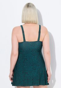 Une robe patineuse avec un imprimé léopard teal, des bretelles réglables, une jupe évasée et une texture lisse, conçue pour un ajustement confortable.