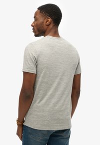 Camiseta gris de cuello redondo hecha de material suave, con mangas cortas y un ajuste relajado, con una textura sutil y sin patrones visibles.