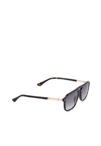 Lunettes de soleil avec verres à dégradé foncé et monture à motif écaille avec des branches fines dorées sur fond blanc.