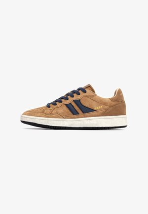 Bruine suède sneakers met marineblauwe accenten, platte veters, geperforeerde neus en een gestructureerde witte tussenzool. Zwarte rubberen buitenzool voor grip.