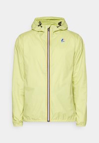 Jasnożółta wodoodporna kurtka z kapturem, przednim zamkiem błyskawicznym z niebiesko-czerwono-białym paskiem oraz elastycznymi mankietami. Logo K-Way na piersi.