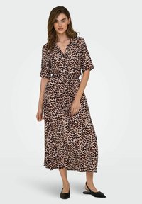 Robe maxi à imprimé léopard, avec des manches courtes, un devant à boutons et une ceinture à nouer. Le tissu a une texture lisse et un motif audacieux.