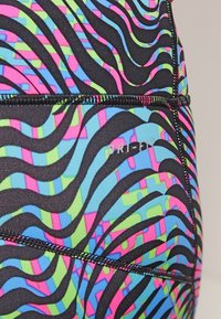 Maillot de bain multicolore avec une base noire, présentant des motifs ondulés en bleu, vert et rose. Inclus des coutures contrastantes et un détail de logo.