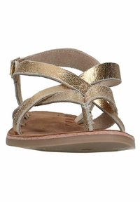 Gouden leren sandalen met kruislings banden, een platte bruine zool en verstelbare gespdetails. Soepele textuur met een metallic afwerking.