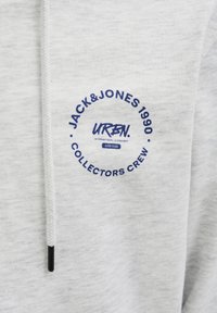 Sudadera gris de cuello redondo hecha de material suave, con un gráfico circular en navy que dice: "JACK&JONES 1990 COLLECTORS CREW."