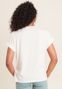 Weißes Kurzarm-T-Shirt mit umgeschlagenen Ärmeln, mit lockerer Passform und weichem Material. Einfaches Design ohne sichtbare Muster oder Akzente.