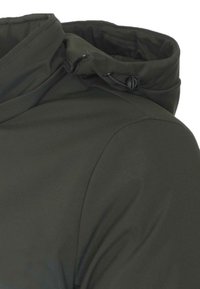 Spalla e colletto di giacca verde scuro con cordoncino regolabile su sfondo bianco.