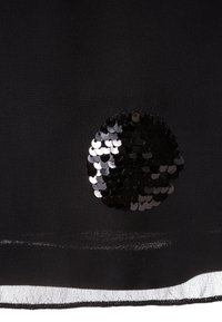 Fond en tissu noir présentant un patch circulaire de sequins noirs brillants, créant un accent texturé. Bords finis avec un subtil éclat.