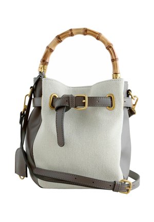 Beige canvas and taupe leather handbag with bamboo handle, gold-tone buckle accents, and an adjustable shoulder strap.