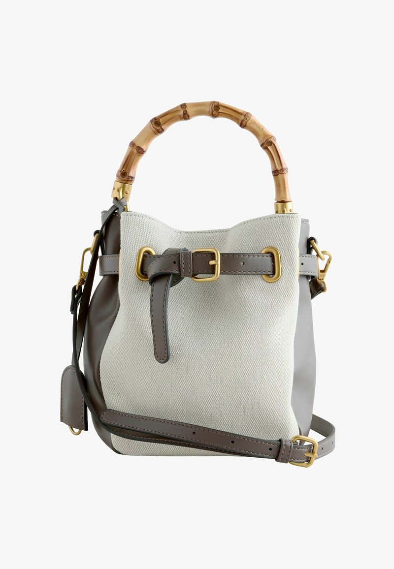Sac à main en toile beige et cuir taupe avec poignée en bambou, boucles dorées et bandoulière réglable.