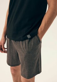 Czarna koszulka bez rękawów połączona z szarymi szortami. Szorty wykonane są z lekkiego, elastycznego materiału i mają boczne kieszenie, a także małą metkę z logo.