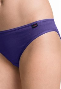 Slip in cotone viola con una texture liscia, caratterizzato da un piccolo etichetta nera con ricamo floreale sulla vita.