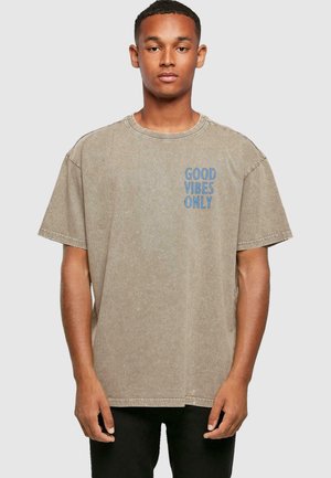 Grå oversized t-shirt med rund halsudskæring og korte ærmer. Har teksten "GOOD VIBES ONLY" trykt i blåt på venstre side. Fremstillet af bomuldsstof.