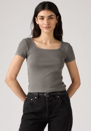 Haut gris à manches courtes côtelé avec un décolleté carré, associé à un jean noir taille haute avec une ceinture et des accents de boutons.