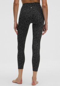 Juodos, aukštu liemeniu, tamprės su sudėtingu gėlių raštu, pagamintos iš tamprios medžiagos, siaurėjančios ties kulkšnimis, su lygiu paviršiumi.