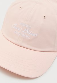 Ροζ ανοιχτό ροζ καπέλο Adidas με λευκή κεντημένη επιγραφή "Adidas Good Drives Golf Dept." στην μπροστινή πλευρά.