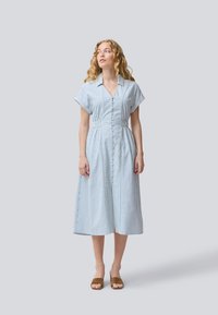Abito a camicia a righe in blu chiaro e bianco. Maniche corte, vita aderente, gonna fluida che arriva fino al polpaccio. Tessuto morbido al tatto.
