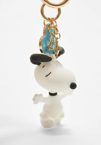 Porte-clés Snoopy en plastique blanc, avec des accents noirs sur les oreilles et le nez. Attaché à un porte-clés en métal doré avec un charme bleu.