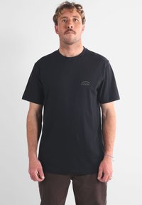 T-shirt noir à manches courtes en coton, avec un petit logo sur la poitrine. Encolure classique et coupe décontractée.