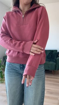 Rózsaszín színű, fél cipzáras pulóver, bordázott textúrával és testhezálló mandzsettával, laza világoskék farmernadrággal párosítva.