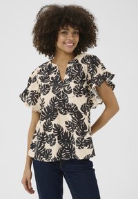 Blusa a maniche corte realizzata in tessuto leggero con uno sfondo crema e una grande stampa di foglie nere; presenta un scollo a V e dettagli arricciati.