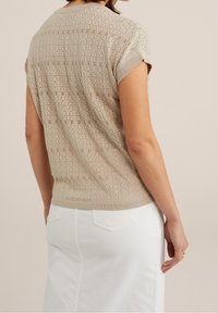 Beige, stickad kortärmad topp med ett strukturerat mönster, avslutad med rund halsringning och ribbad nederkant, kombinerad med en vit jeanskjol.