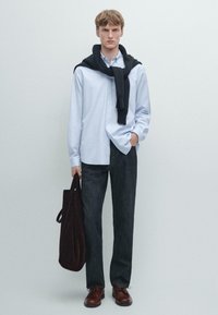 Lichtblauwe overhemd, donkere denim broek, zwarte trui over de schouders, bruine schoenen, bordeauxrood tas. Eenvoudig, strak design.